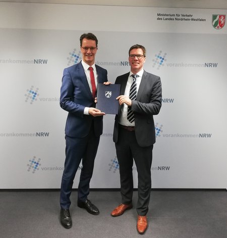 NVR-Verbandsvorsteher Stephan Santelmann und NRW-Verkehrsminister Hendrik Wüst mit dem Förderbescheid